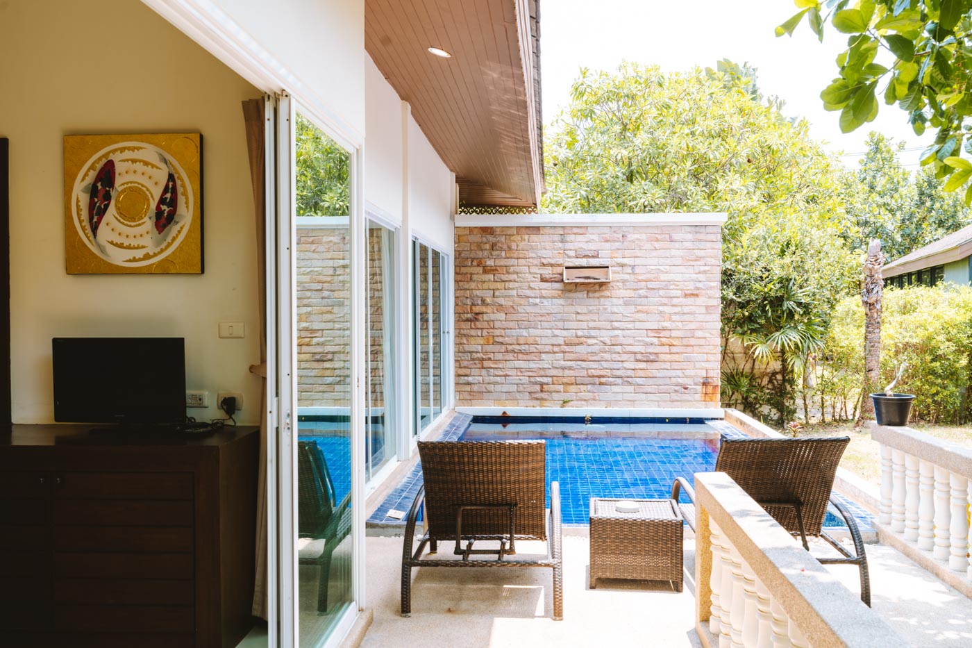 Terrazza privata a bordo piscina della villa con posti a sedere all'aperto e giardino tropicale