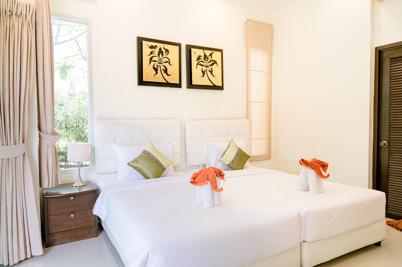 Lussuosa camera da letto privata in villa con due letti singoli, cuscini decorativi e opere d'arte a parete